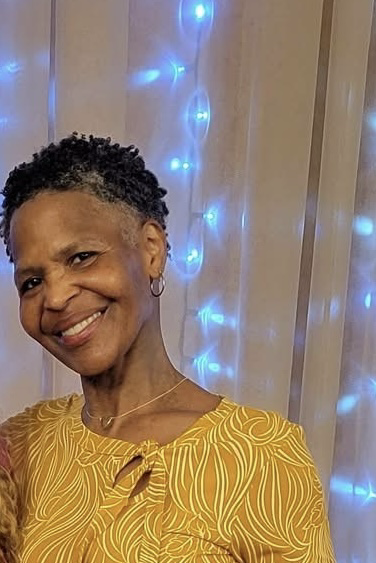 Portrait of Ms. Victoria Trotter smiling in a yellow blouse