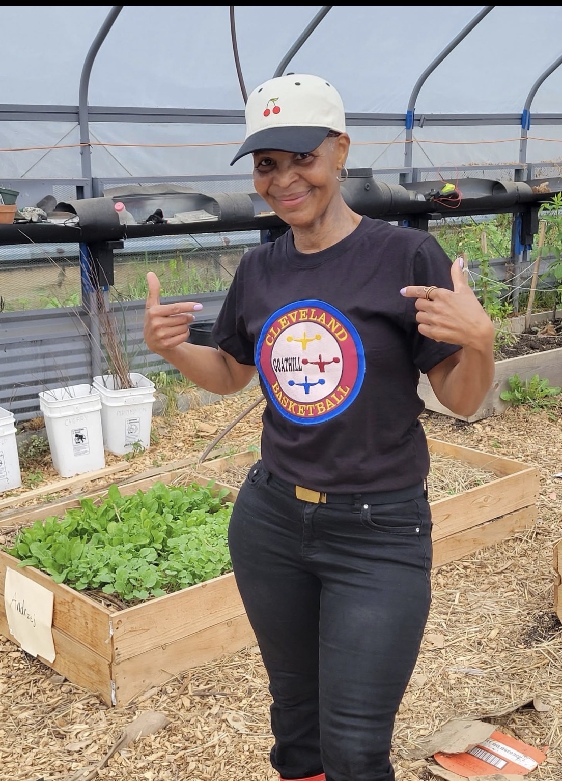 Ms. Victoria Trotter standing beside garden beds in a greenhouse